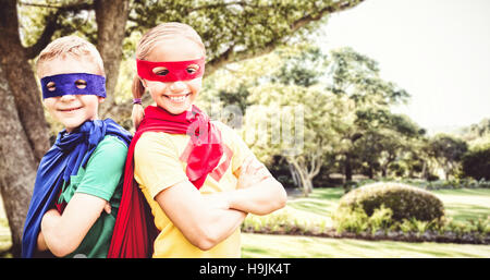 Composite image of happy brother and sister in cape and eye mask Stock Photo