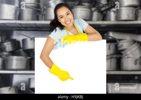 Composite image of happy cleaning lady pointing to white surface Stock Photo
