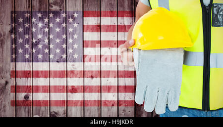 Composite image of construction worker holding gloves and hardhat Stock Photo