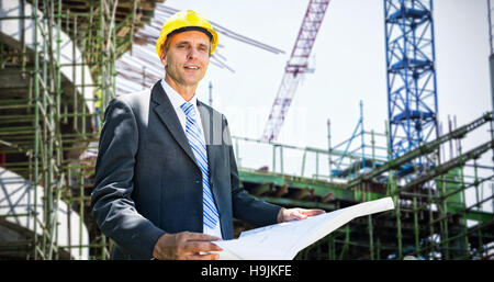 Composite image of portrait of smiling architect holding blueprint Stock Photo