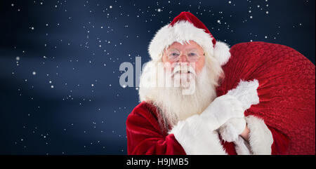 Composite image of jolly santa carries his sack Stock Photo