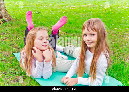 Photo of two girls sitting on grass in summer Stock Photo