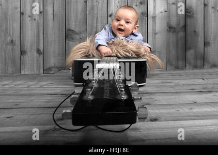 baby boy on wooden rustic stage laying on guitar Stock Photo