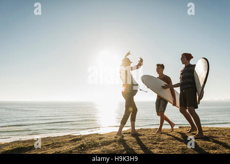Three friends with surfboards camping at seaside Stock Photo