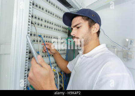 focused electrician applying safety procedure while working on electrical panel Stock Photo