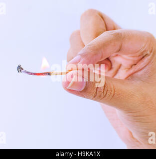 Hand holding a fired matchstick on a white background Stock Photo