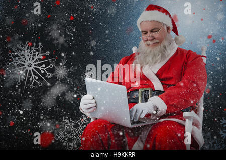 Composite image of santa claus typing on laptop against white background Stock Photo