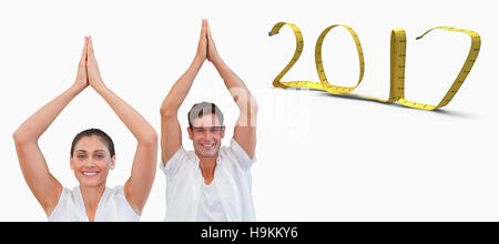 3D Composite image of peaceful couple in white doing yoga together with hands raised Stock Photo