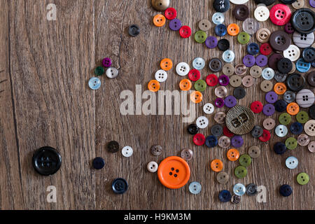 Random Scattering of small multicolored buttons on a wooden floor boards. Stock Photo