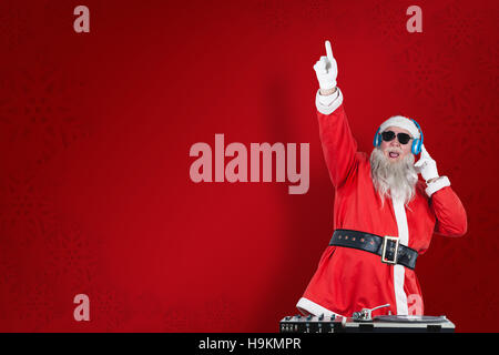 Composite image of santa claus playing dj with raised hand Stock Photo