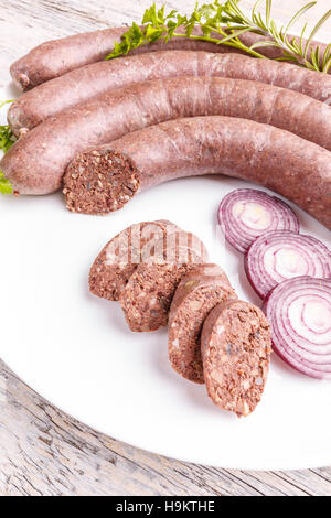 Black pudding with cut slices on white plate Stock Photo