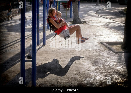 Mother child swing. Young mother and her infant child playing on the recreation park swings. Thailand S. E. Asia Stock Photo