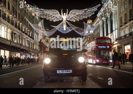 LONDON - NOVEMBER 18, 2016: Traditional black taxi waits for customers under twinkling Christmas angels lighting on Regent St. Stock Photo