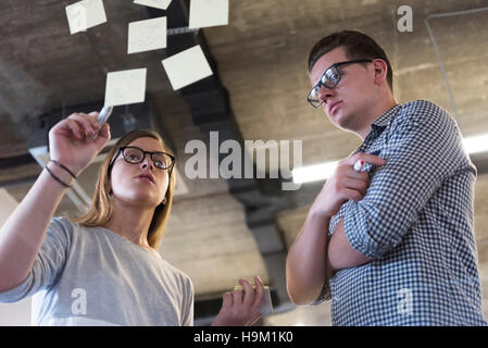 start up business planning and making organization with young couple at modern office interior writing notes on stickers Stock Photo
