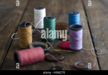 Bobbins with colorful threads on old wooden table background, Stock Photo