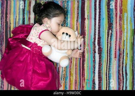 Little girl sleeping on a colorful rug. Stock Photo