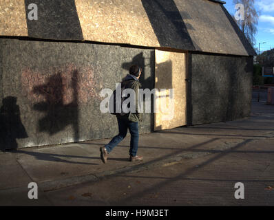 low winter sun on urban single person walking alone shadows of traffic lights Stock Photo