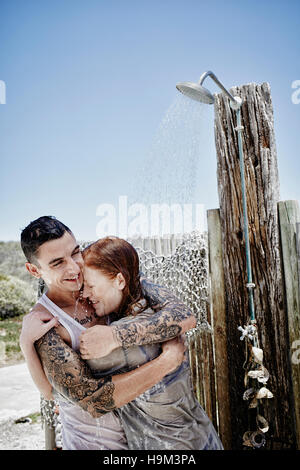 Young Couple Taking Shower On The Beach With Clothes Stock Photo - Alamy