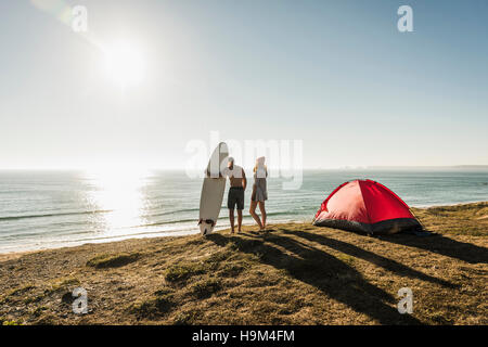 Young couple with surfboard camping at seaside Stock Photo