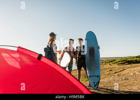 Three friends with surfboards camping at seaside Stock Photo