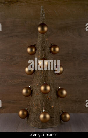 Decorative Christmas tree made from straw  with golden balls isolated on wooden background Stock Photo