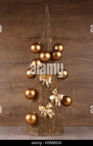 Decorative Christmas tree made from straw  with golden balls and bows isolated on wooden background Stock Photo