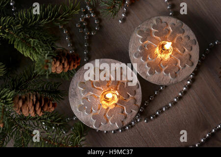 Silver Christmas candles decorated with snowflakes near christmas tree, garlands. Top view. Candlelight. Stock Photo