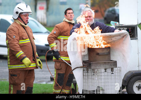 Health and Safety on site fire training using a fire blanket to extinguish a pan of oil under guidance UK Stock Photo