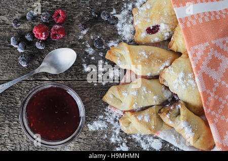 Baking with jam from berries on a wooden board in rustic style decorated with frozen berries. Top view. Vintage style. Natural light. Homemade baking. Stock Photo