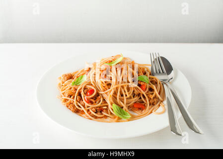 Spaghetti with Bolognese sauce and basil served on a white plate Stock Photo