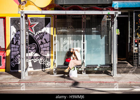 Woman at a bus shelter in San Francisco, California Stock Photo