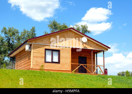 The wooden house with a lawn on a background of the blue sky Stock Photo