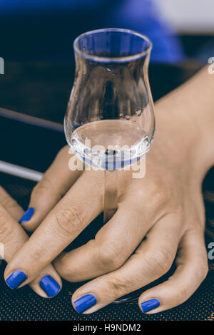 A Glass of Grappa in Woman’s Hands. Grape Brandy or Schnapps on the Table. Stock Photo