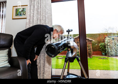 Looking through telescope in daytime spying on neighbours neighbors UK England GB Stock Photo