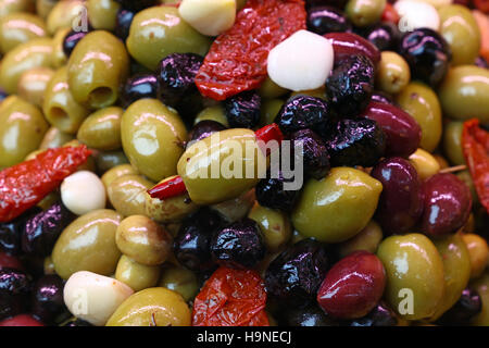 Mediterranean salad mix of assorted whole Italian olives (black, green, red) with garlic, hot pepper and sundried tomato in oil close up, low angle vi Stock Photo