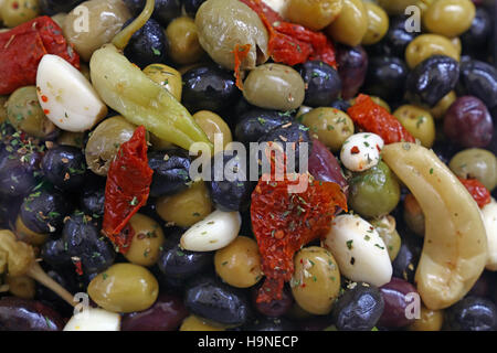 Mediterranean salad mix of assorted whole Italian olives (black, green, red) with garlic, hot pepper and sundried tomato in oil close up, elevated hig Stock Photo