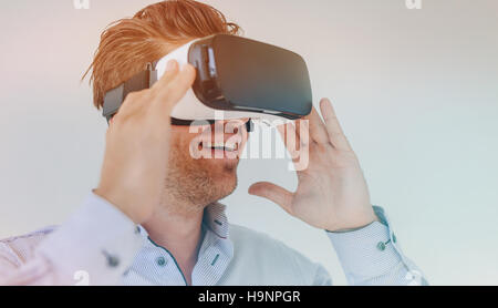 Closeup shot of young businessman using the virtual reality headset and smiling. Male executive wearing VR goggles. Stock Photo