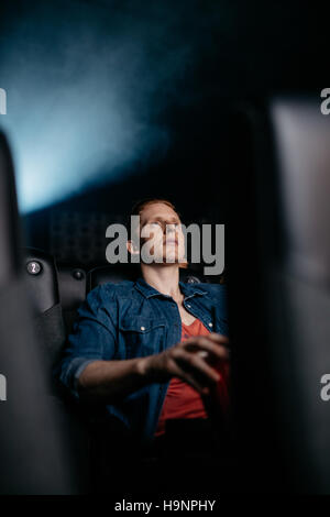 Young man watching movie in theater. Caucasian male watching film in multiplex cinema. Stock Photo