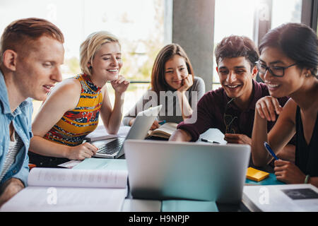 Multiracial group of young students studying in the library. Young people sitting together at table with books and laptop for researching information Stock Photo
