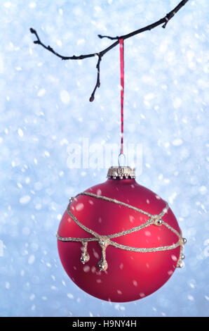 Red xmas ornaments on blue blurred bright holiday background creative concept with space for text under the snow. Christmas decorations on the branche Stock Photo