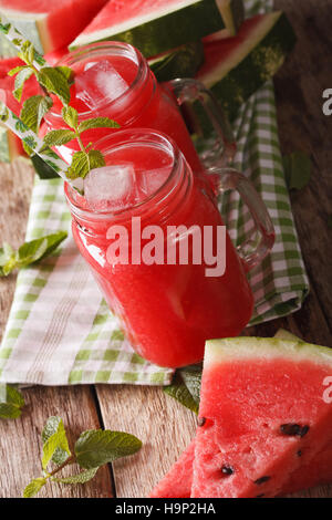 Freshly prepared watermelon juice with ice and mint close up in a glass jar on the table. vertical Stock Photo