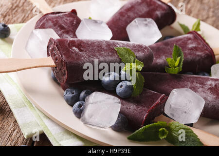 tasty blueberry popsicles on a stick macro on a plate on the table. horizontal Stock Photo