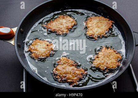 Frying latkes with ready side up in deep oil on the pan from side Stock Photo