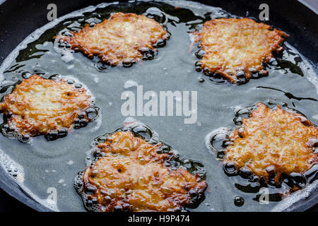 Frying latkes with ready side up in deep oil on the pan from side closeup Stock Photo