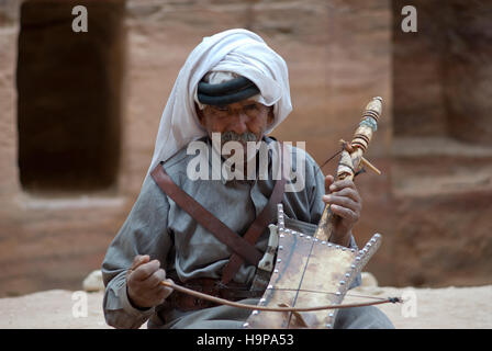 Bedouin senior man playing stringed instrument at the ancient site of Petra in Jordan Stock Photo