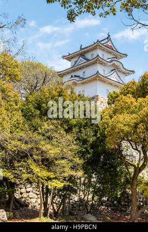 Japan, Akashi castle, AKA Kishun-jo. three-story Hitsujisaru Yagura, turret, with trees surrounding. Spingtime, blue but partly cloudy sky. Stock Photo