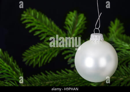 Silver white bauble, a spherical Christmas ornament, usually hung on Christmas tree.  Christmas ball, a Xmas tree decoration. Stock Photo
