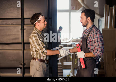 profession, technology and people concept - two workmen with tablet pc computer at workshop Stock Photo