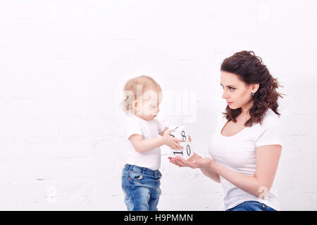Mother and daughter playing with blocks. On cubes have numbers. Family education. Mother and daughter dressed in jeans and white T-shirts. Family look Stock Photo