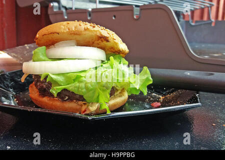 Homemade hamburger. Gas grill on background. Stock Photo